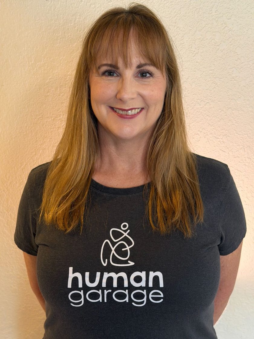 Katy Grindal, body resilience coach, smiling in a Human Garage shirt